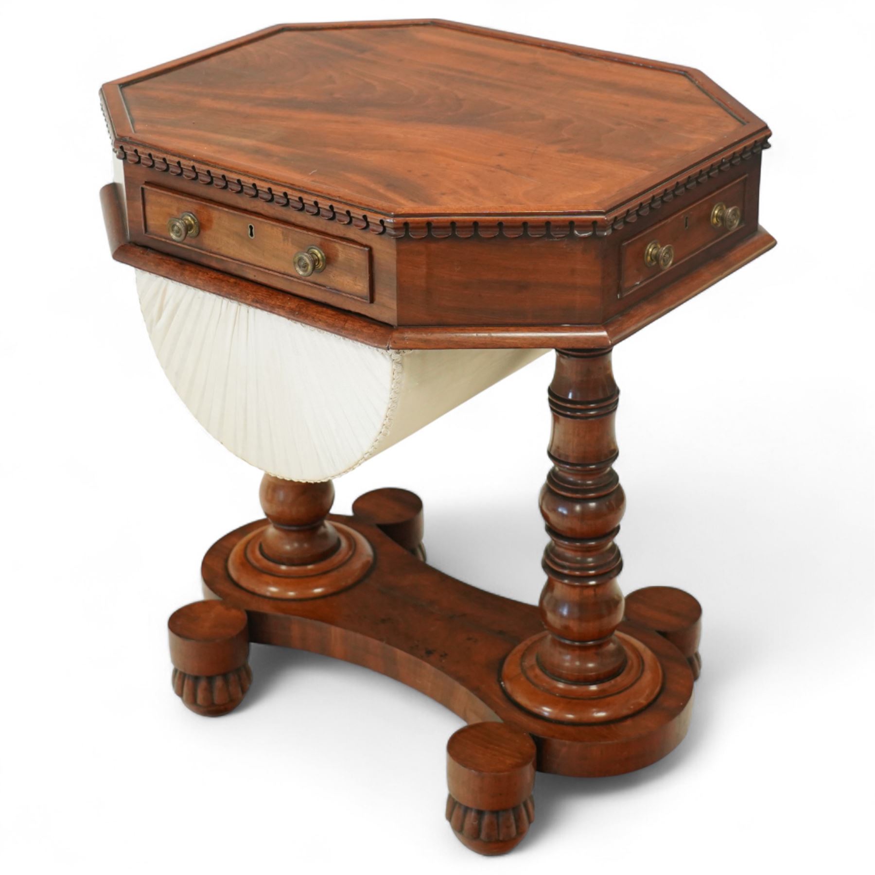 William IV mahogany work table, the octagonal top with ebony line inlay and dentil moulded edge, fitted with four small drawers to the frieze, above a silk-pleated sliding work basket, all raised on a turned column supports and shaped platform base with rounded feet, circa 1835