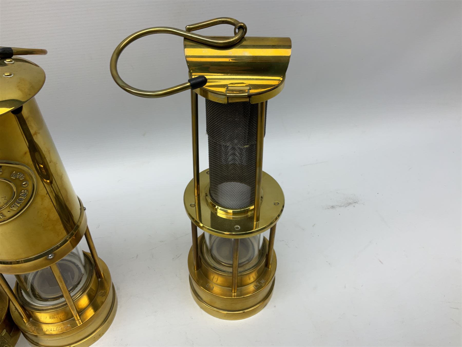 Four miners lamps, comprising Clanny miners lamp, with flip top and gauze protected by three rods, stamped E.T.W E-3, lamp with a gauze chamber protected by three rods, and two E. Thomas & Williams Ltd lamps, tallest example H26cm