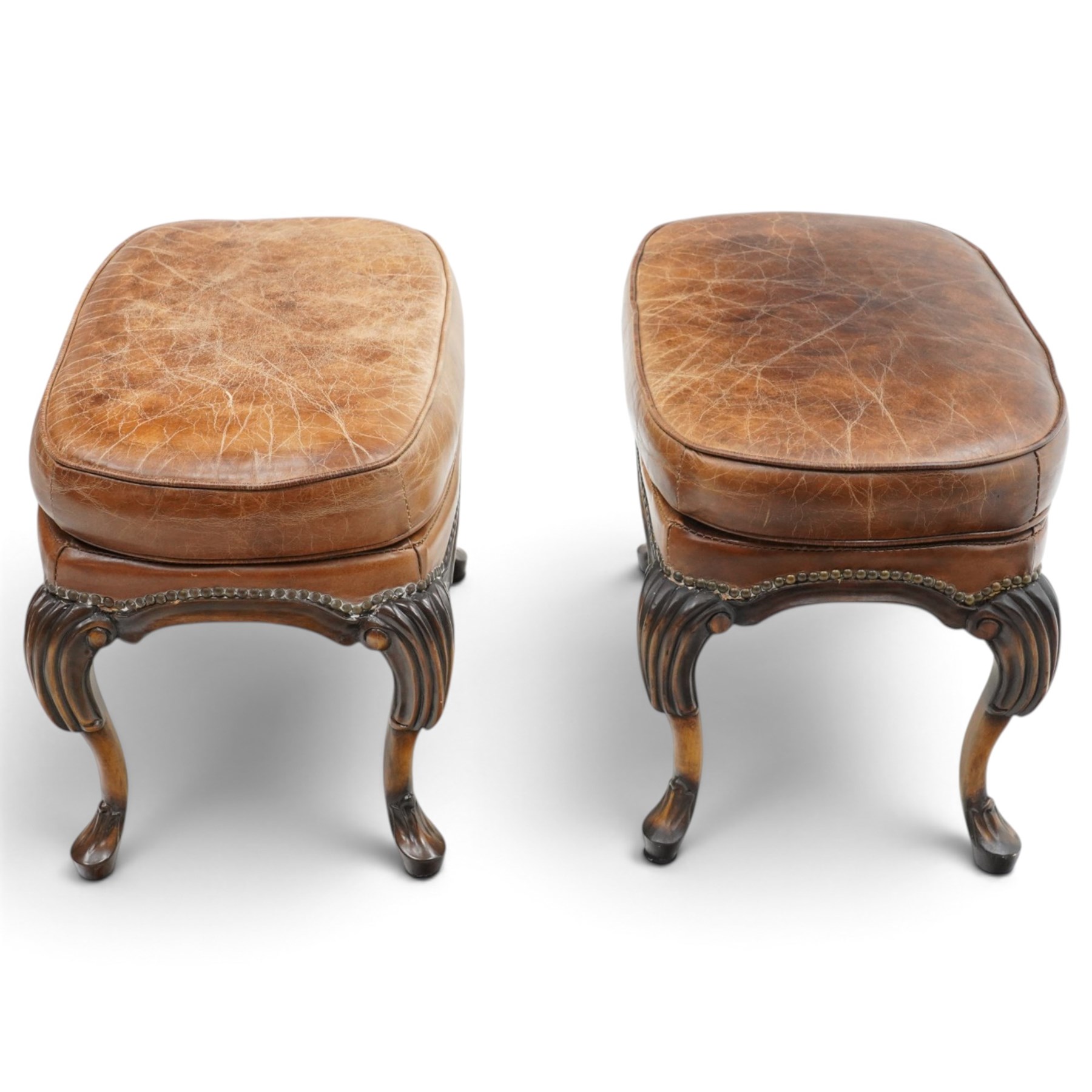 Pair of quality Queen Anne design mahogany framed wingback armchairs with matching footstools, the high sprung winged backs over rolled arms with studwork, raised on elegant reeded scroll carved cabriole supports, upholstered in deep chocolate brown leather (W82cm D75cm H112cm), the footstools with ovoid padded seat over studwork and moulded lower rail and cabriole supports (W65cm D42cm H48cm)