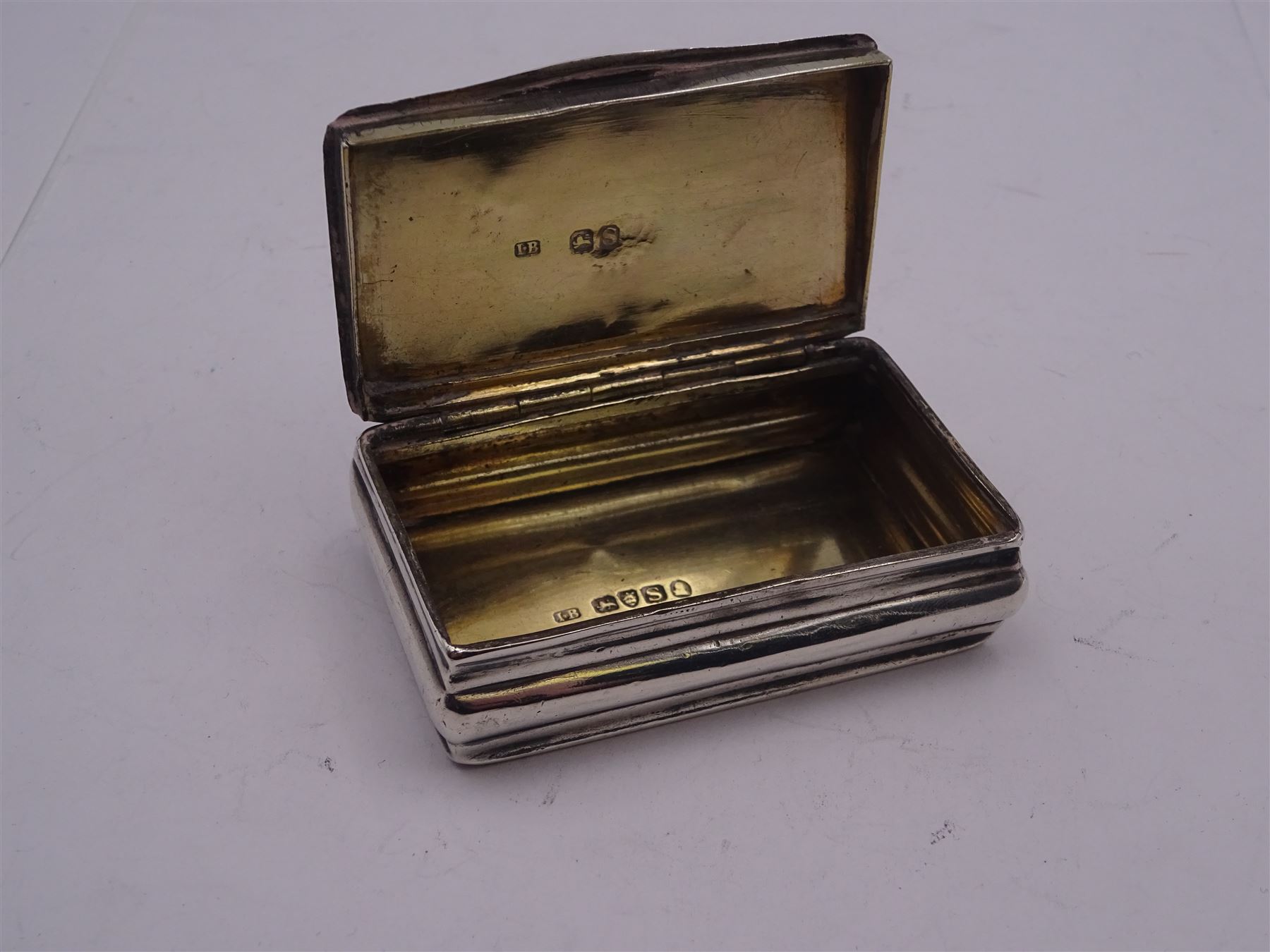 George III silver snuff box, of rectangular form with foliate engraved panel to hinged cover and underside of body, opening to reveal a gilt interior, hallmarked London 1813, makers mark I.B, W6.5cm, approximate 1.86 ozt (57.6 grams)