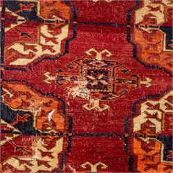 Vintage Bokhara hand-knotted rug, madder field woven in rows of octagonal Tekke guls arranged in vertical columns, each enclosing angular cruciform devices and tribal motifs, divided by narrow indigo lines, within multiple geometric borders incorporating stepped lozenges and latch hook devices, with cotton fringe ends 