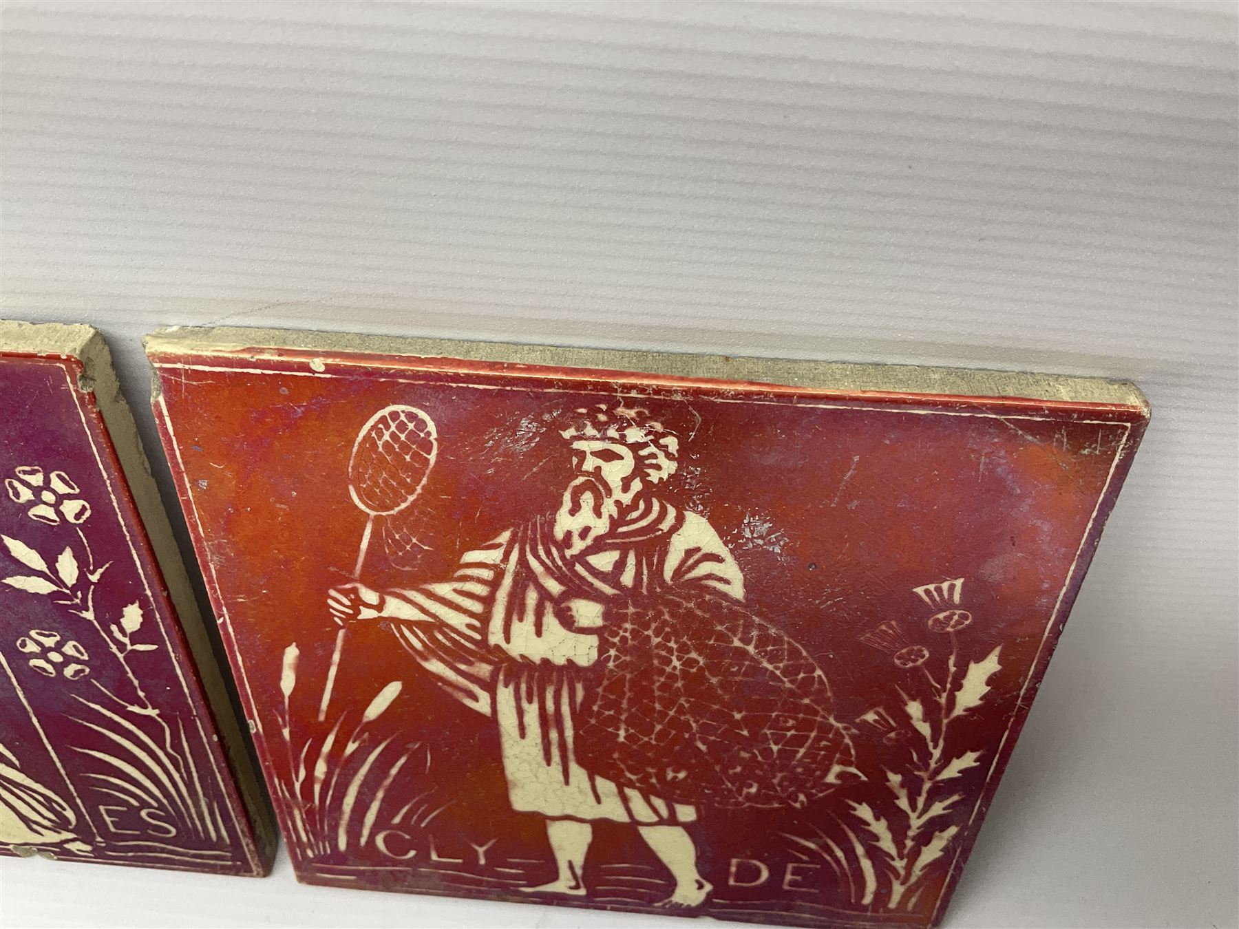 Pair of Maw & Co Benthall Works tiles, each depicting classical figures with fishing and shipping details, one inscribed Thames, the other Clyde, upon a red lustre ground, with raised marks verso, H15.2cm