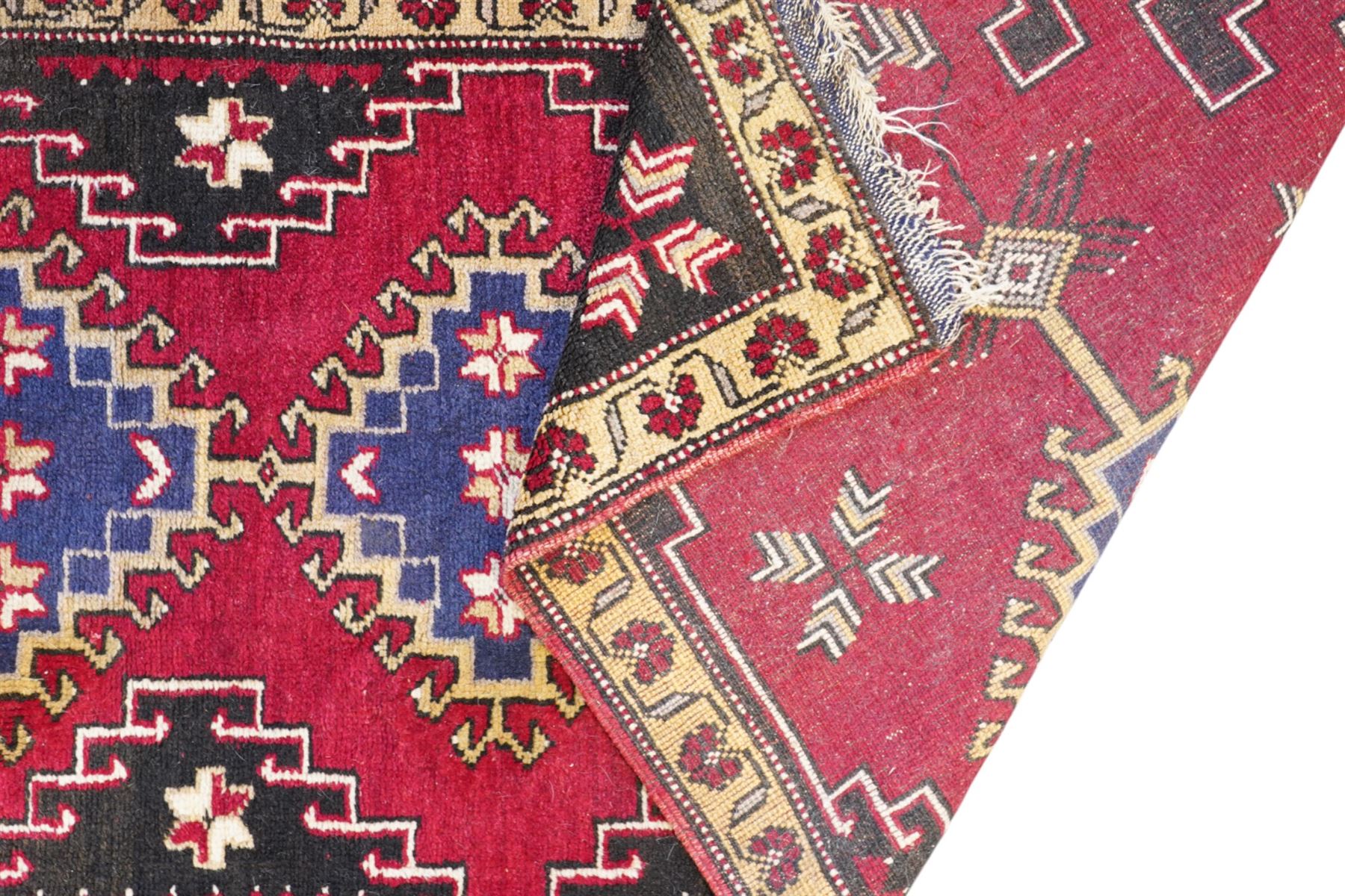 Turkish crimson ground rug, the field decorated with four hooked lozenges, trailing border with stylised flower heads 