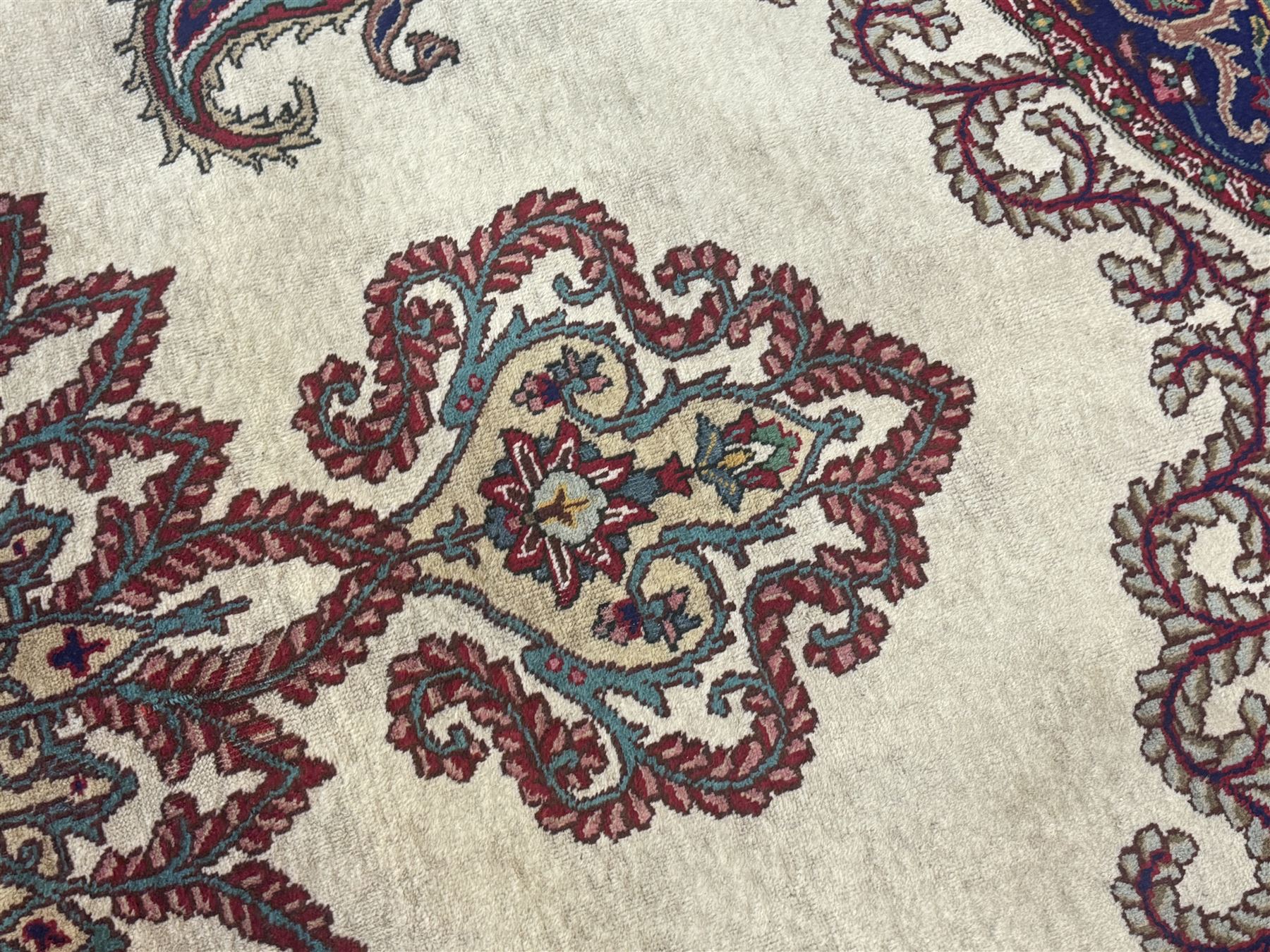 Northwest Persian signed Tabriz ivory ground carpet, central medallion with intricate floral motifs, the field and spandrels decorated with scrolling tendrils and palmettes, ivory main border with crimson and indigo floral decorations, surrounded by crimson guard bands