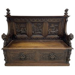 19th century heavily carved oak settle, the moulded upper rail over triangular foliage carved frieze, three Flemish style carved panels depicting tavern scenes, acanthus carved uprights terminating to lion carved arms, hinged box seat, the panelled front carved with lion masks and extending scrolled acanthus leaves, on moulded skirt base