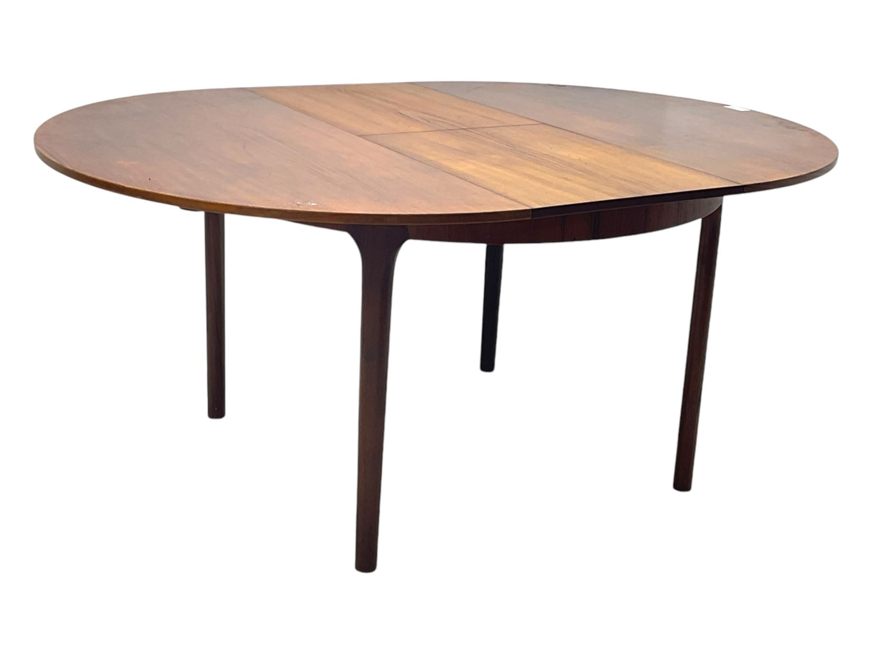 Mid-20th century teak extending dining table, circular top with pull-out extension and concealed leaf extension mechanism, on tapered supports; set of four teak dining chairs with black vinyl padded seats 