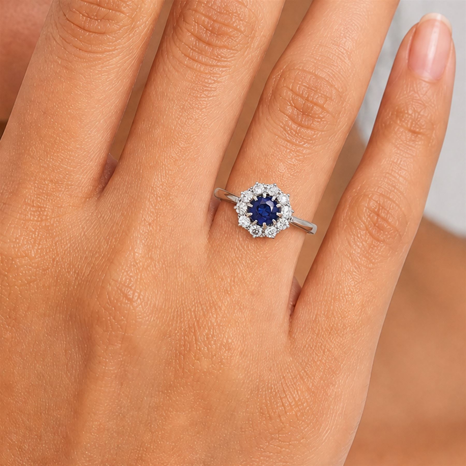 Platinum sapphire and diamond cluster ring, single round cut sapphire of approx 0.85 carat, surrounded by ten round cut diamonds, total diamond weight approx 0.40 carat