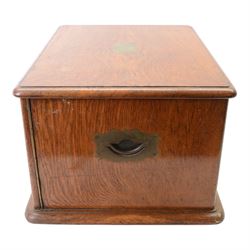 Oak table top canteen cabinet, the top with inset vacant brass cartouche, with pair of panelled doors opening to reveal four interior drawers with inset brass handle, containing a selection of silver plated flatware, 29cm x 40cm x 51cm