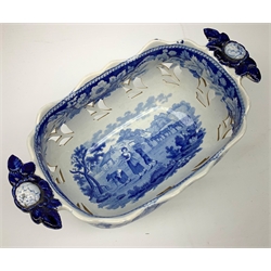 Mid 19th century blue and white transfer printed pearlware reticulated chestnut basket, of oval form with twin handles, decorated to the interior with figures before a classical temple within a garden setting, including handles W26cm, together with a mid 19th century blue and white transfer printed pearlware stand with reticulated edge, decorated with a Willow Pattern, L25cm, and a John and William Ridgeway blue and white transfer printed twin handled pierced basket, decorated with a pastoral scene containing figures at work, with printed mark beneath, including handles L25cm