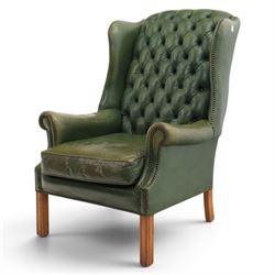 20th century green leather wingback button backed armchair, brass studded trim, with scrolled arms raised on oak supports
