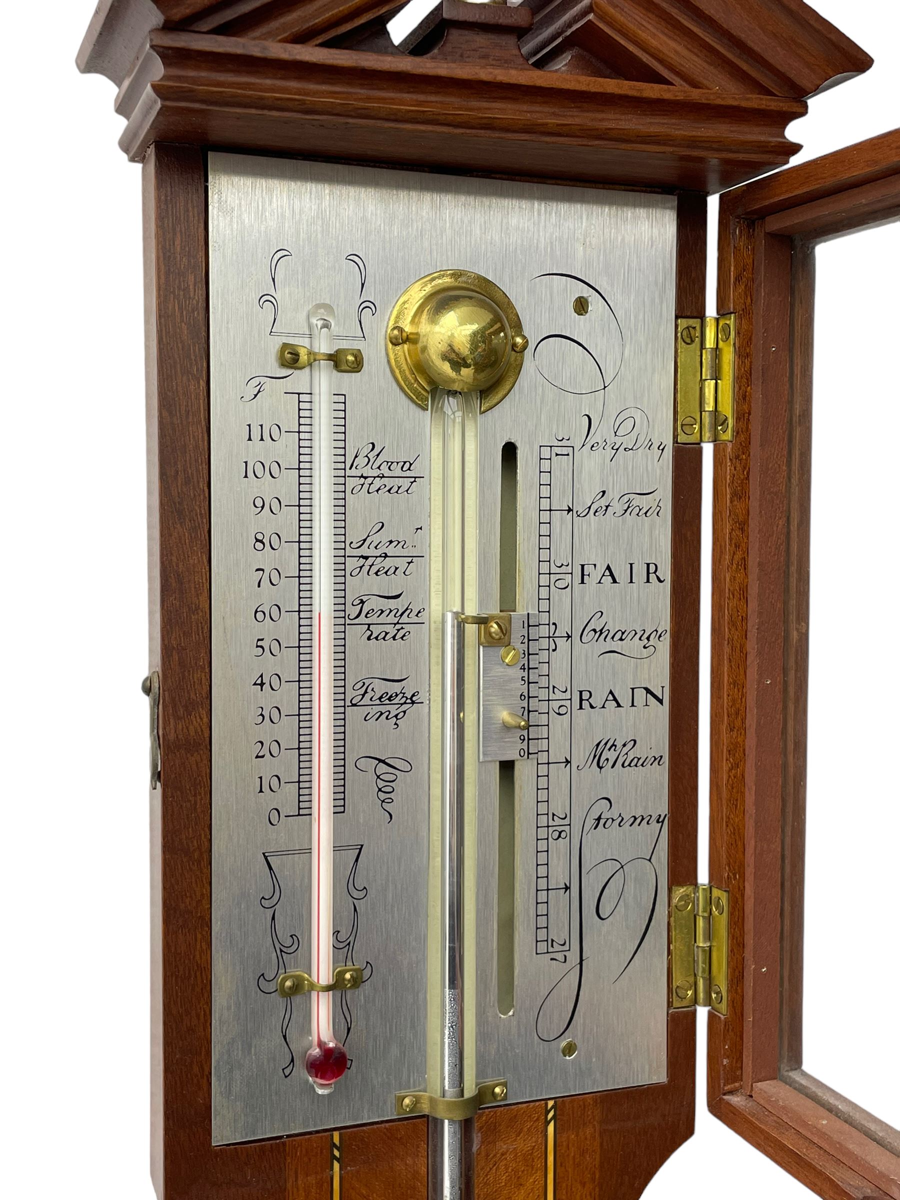 20th century - mercury cistern barometer in an 18th century style mahogany case with contrasting inlay and a broken pediment, round base with a turned cistern cover, fully exposed glass tube and silvered register within a glazed door, with a Fahrenheit spirit thermometer, engraved weather predictions and sliding vernier. Mercury clean and present.
