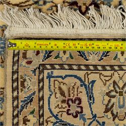 Central Persian fine Nain hand-knotted rug, ivory ground, with a central shaped floral medallion with pendants, surrounded by scrolling foliate and floral motifs incorporating rosettes, palmettes and delicate vine work in blue, cream and beige tones, enclosed by blue spandrels and an ivory border with repeating palmettes and meandering vines, flanked by floral guard stripes, with cotton fringes