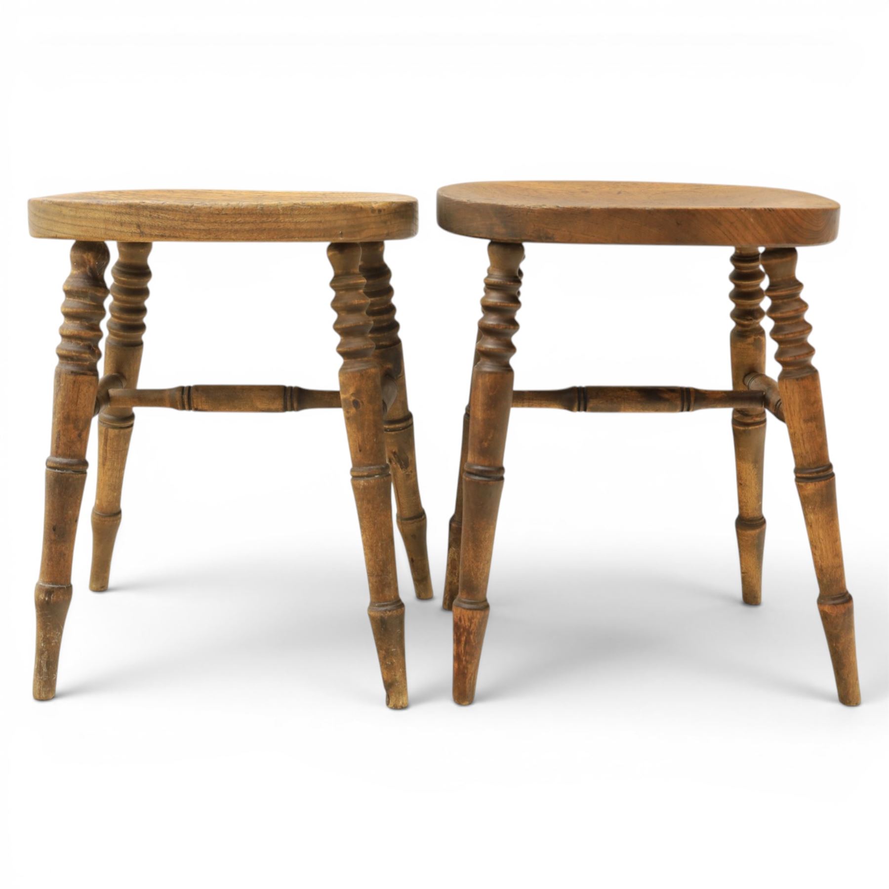 Pair of country elm stools, with oval dished seat raised on turned wooden supports, united by a H-stretcher