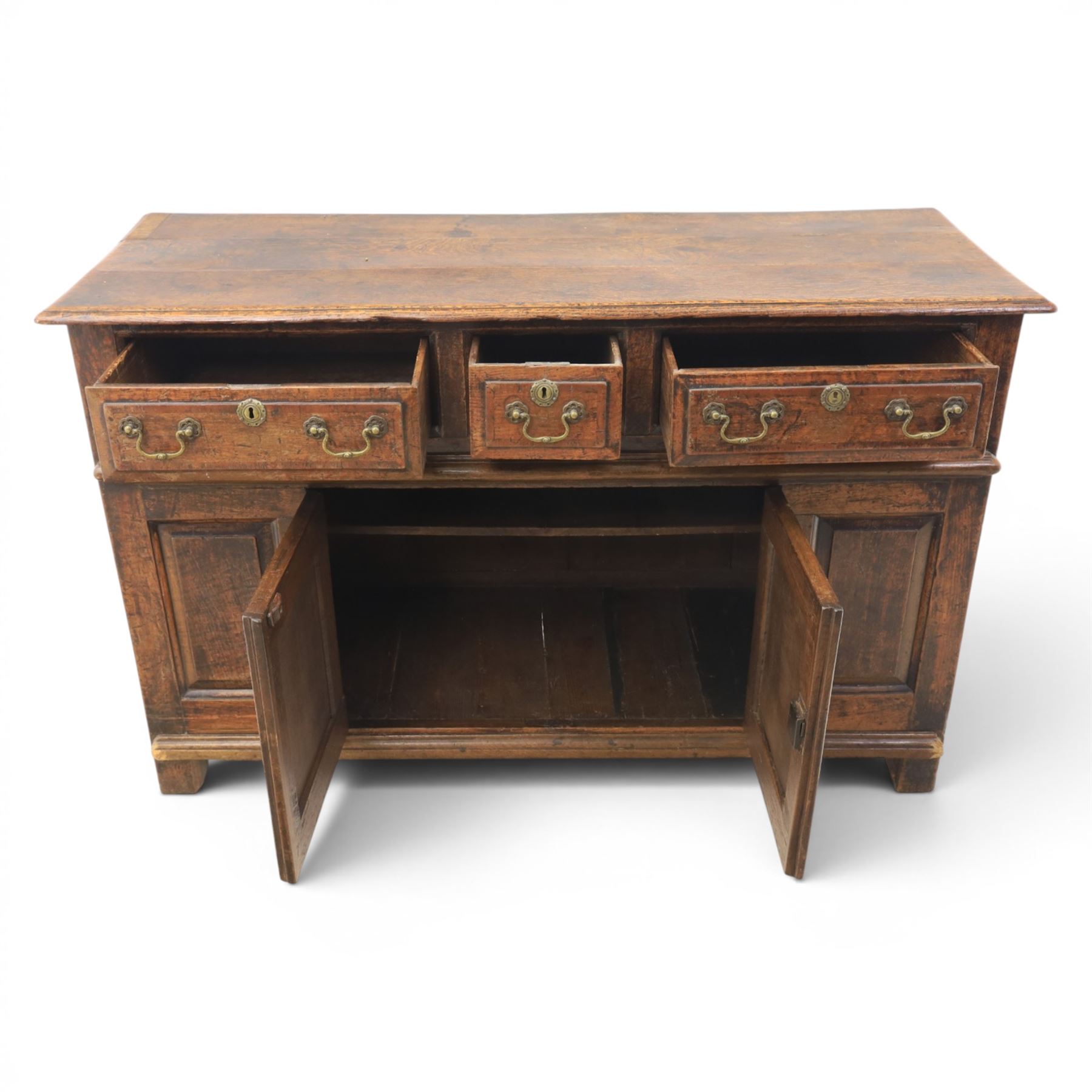 George III oak dresser base, rectangular top with moulded edge, three fielded panelled drawers with brass swan neck handles, over four fielded panelled front with the central two cupboard doors, raised on stile supports