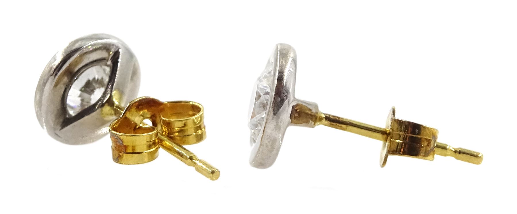Pair of 18ct white and yellow gold round brilliant cut diamond stud earrings, rubbover set, stamped 750, total diamond weight 0.62 carat