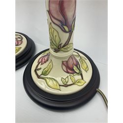 Pair of Moorcroft table lamps of candlestick form in magnolia pattern, with Moorcroft shades, H50cm 

