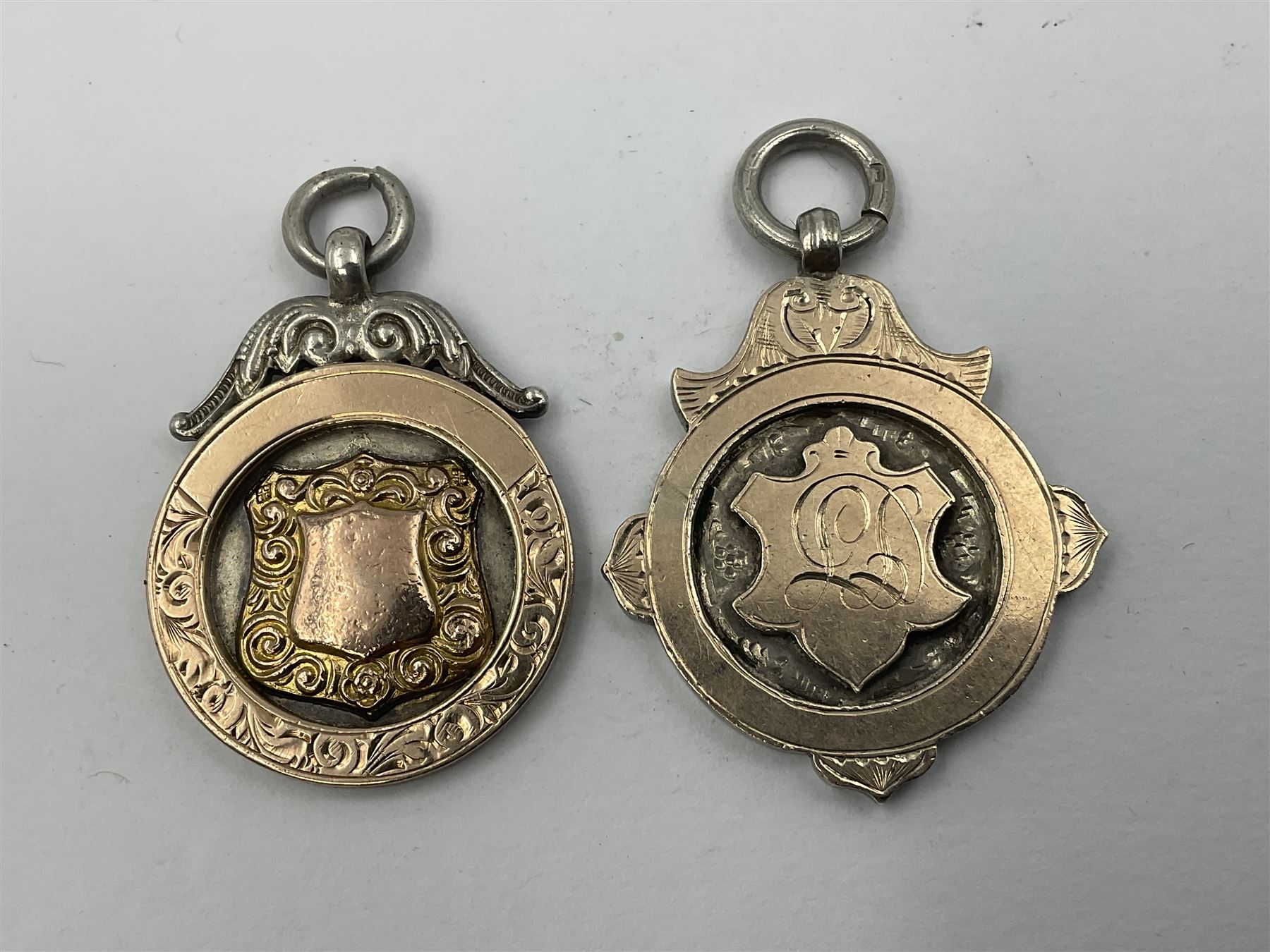 Seven early 20th century silver gold faced cartouche fobs, to include a circular example, with rose gold border and cartouche within an embossed yellow gold border, engraved verso, and a double sided example, all hallmarked with various dates and makers
