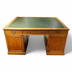 Late 19th century twin pedestal oak partner's desk, rectangular top with inset green leather writing surface, fitted with nine graduating drawers to each side, the rear drawers enclosed by panelled cupboards