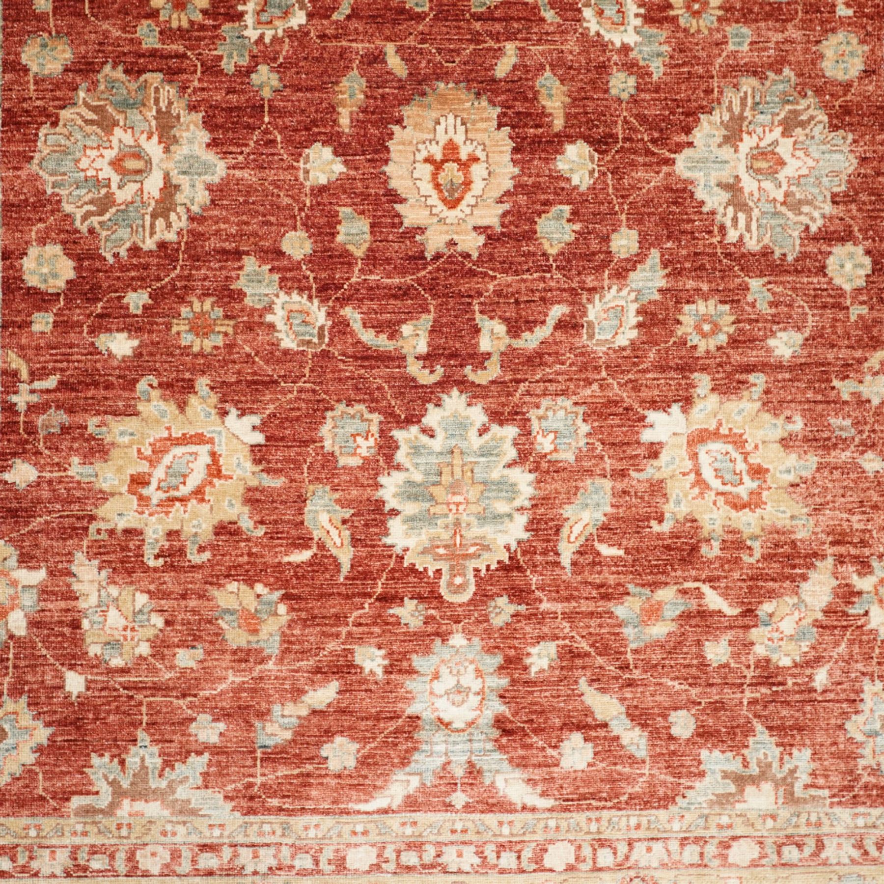 Persian Chubi Oushak style revival hand-knotted carpet, madder red field decorated with large-scale stylized palmettes and floral sprays framed by a broad pale golden border with simplified foliate motifs and multiple guard stripes