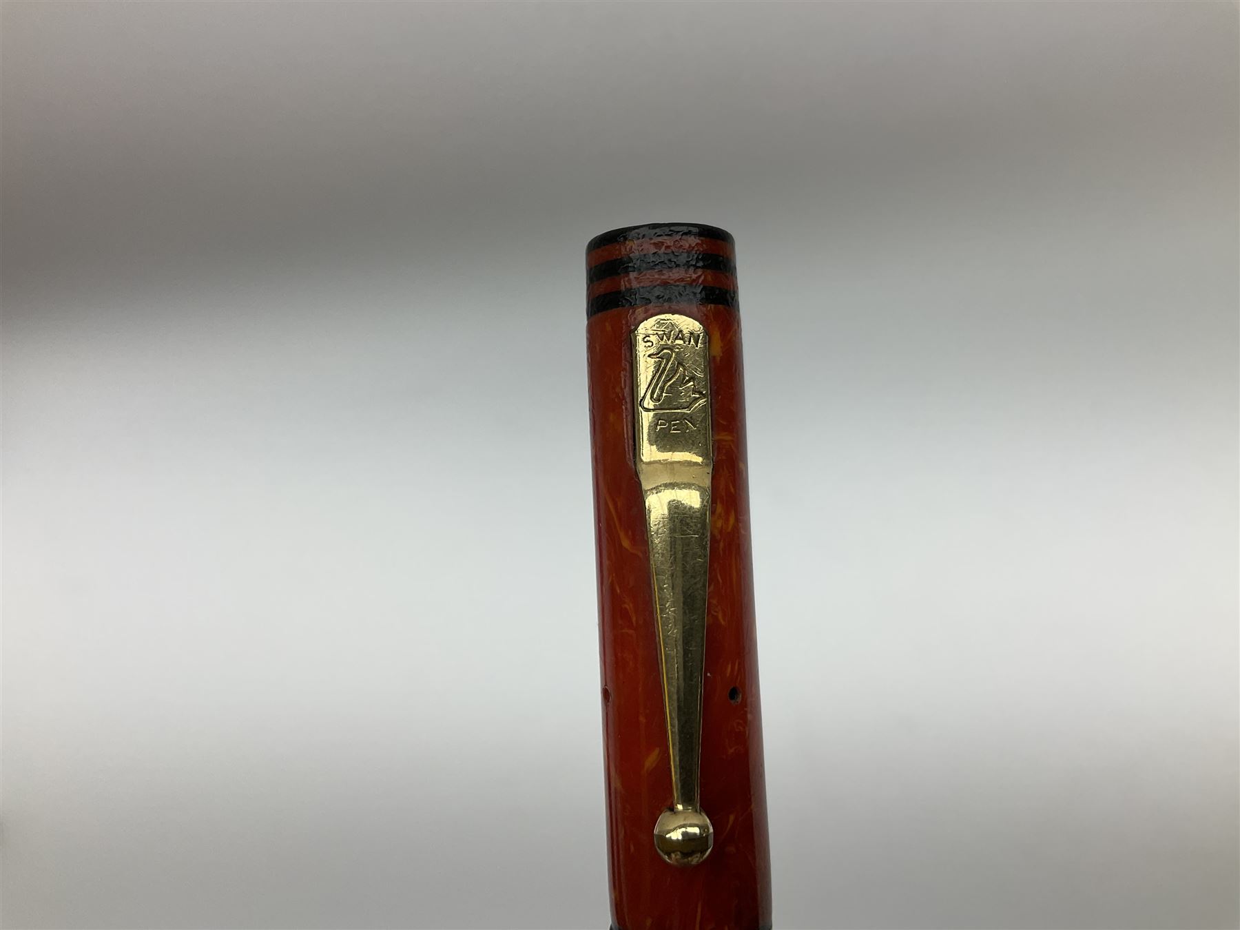 Vintage Swan Mabie Todd lever fill fountain pen in coral red, the nib a/f marked 14K, together with two further vintage Swan Mabie Todd fountain pens, the first example with lever fill, the other leverless, each with black body, one with nib marked 14ct, (3) 