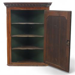 19th century oak wall hanging corner cupboard, moulded cornice above a panelled door enclosing shaped interior shelves, finished in green paint to the backboards