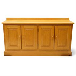 Unicornman - craftsman made oak low-cupboard or sideboard, rectangular top with raised back, fitted with four panelled cupboard doors, on skirted base applied with carved unicorn signature, by Geoff Gell of Coxwold