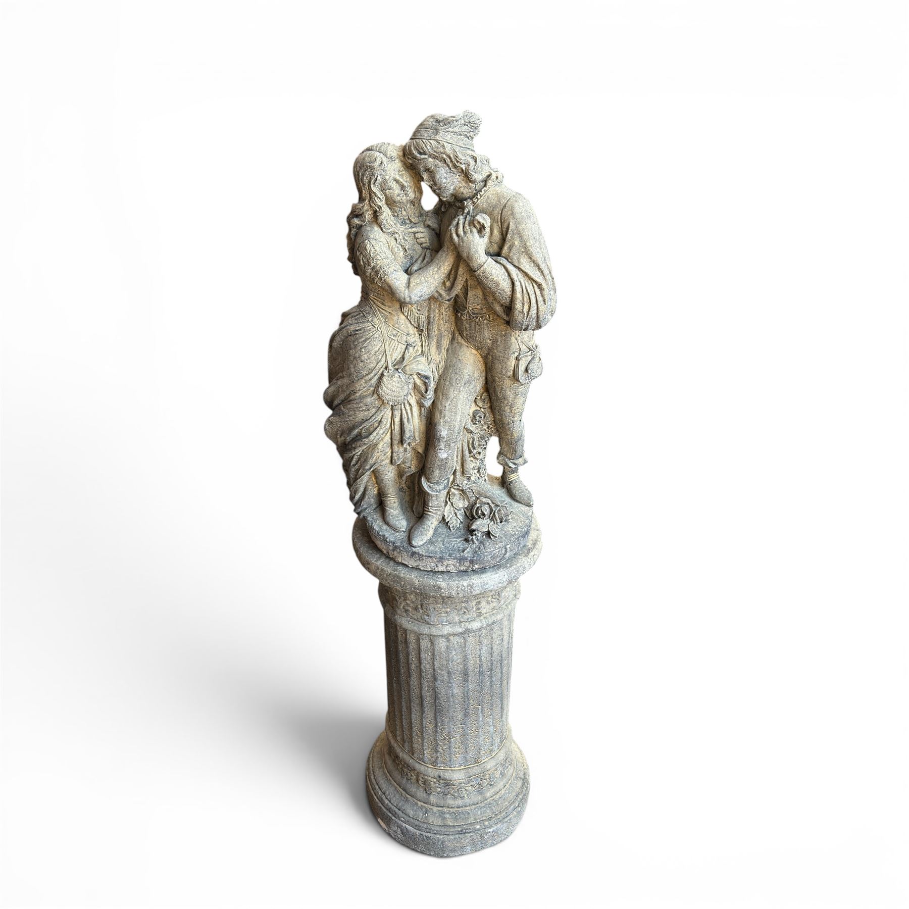Composite garden statue group of Romeo and Juliet embracing, the couple adorned in Medieval dress standing on a naturalistic base with fallen flowers, raised on a Neoclassical fluted pedestal with Anthemion leaf motifs