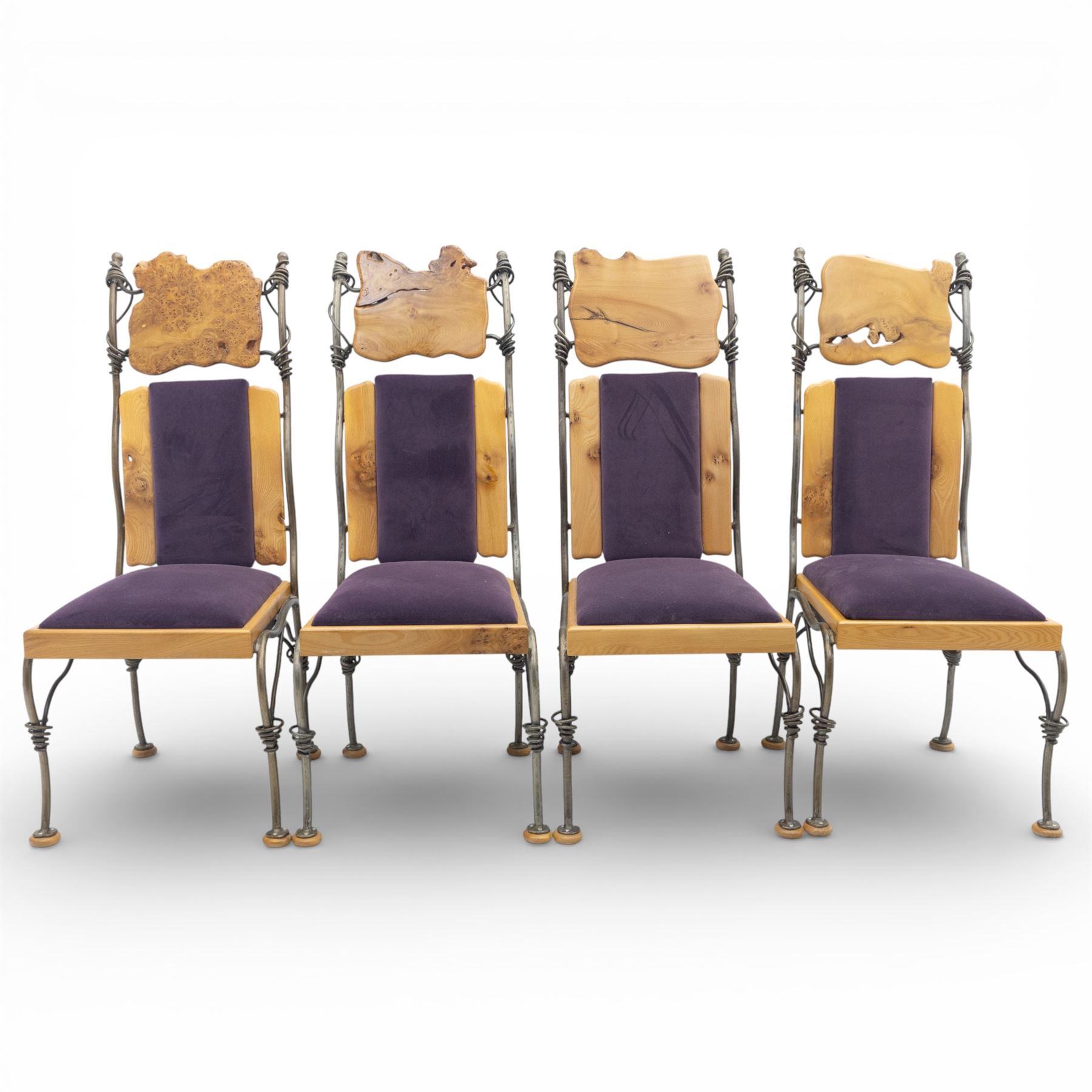 Paul Hodgkiss Designs of Glasgow - contemporary shaped elm dining table with wrought iron base; with set ten (8+2) matching high-back dining chairs, table of organic form above an elaborate wrought iron supports, with central elm stretcher, the chairs with en suite with matching wrought iron work burred elm headrest, purple velour upholstery with drop in seat     

Table: W 102cm, L 243cm, H 74cm
Chairs: W 56cm, D 52cm, H 130cm