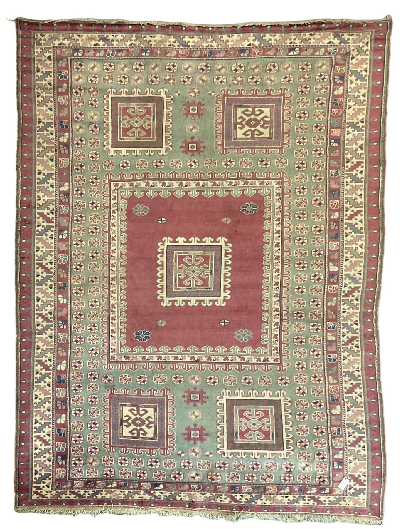 Turkish deep pink and green ground carpet, the square field with hooked borders surrounded by geometric motifs, multi-band border with overall geometric designs 