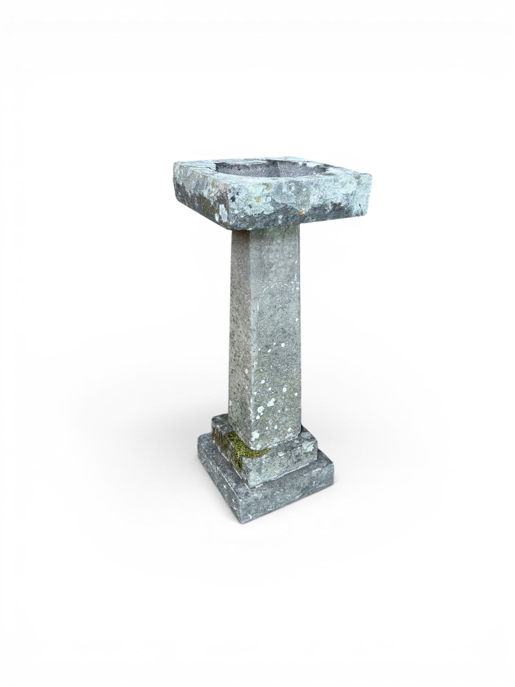 19th century weathered sandstone birdbath, formed in four sections, square top with carved shell bath, raised on tapering column with stepped base