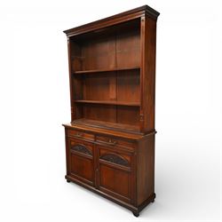 Late Victorian tall walnut open bookcase on cupboard, projecting cavetto cornice over reeded and fluted uprights moulded with roundel motifs, flanking two adjustable shelves, the base fitted with two drawers over panelled cupboards, carved with oakleaf and acorn motifs and grapevines, on bracket feet