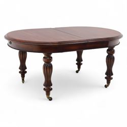 Victorian mahogany extending dining table, rounded rectangular top with moulded edge, pull-out action fitted with two additional leaves, raised on four reeded and fluted baluster legs with brass caps and castors