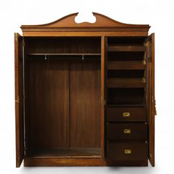 Edwardian walnut triple wardrobe, shaped broken-arch pediment over three doors comprising central mirrored door flanked by moulded raised and fielded panelled doors, interior fitted with hanging space and a bank of three open drawers above three brass recessed-pull drawers, on moulded plinth base