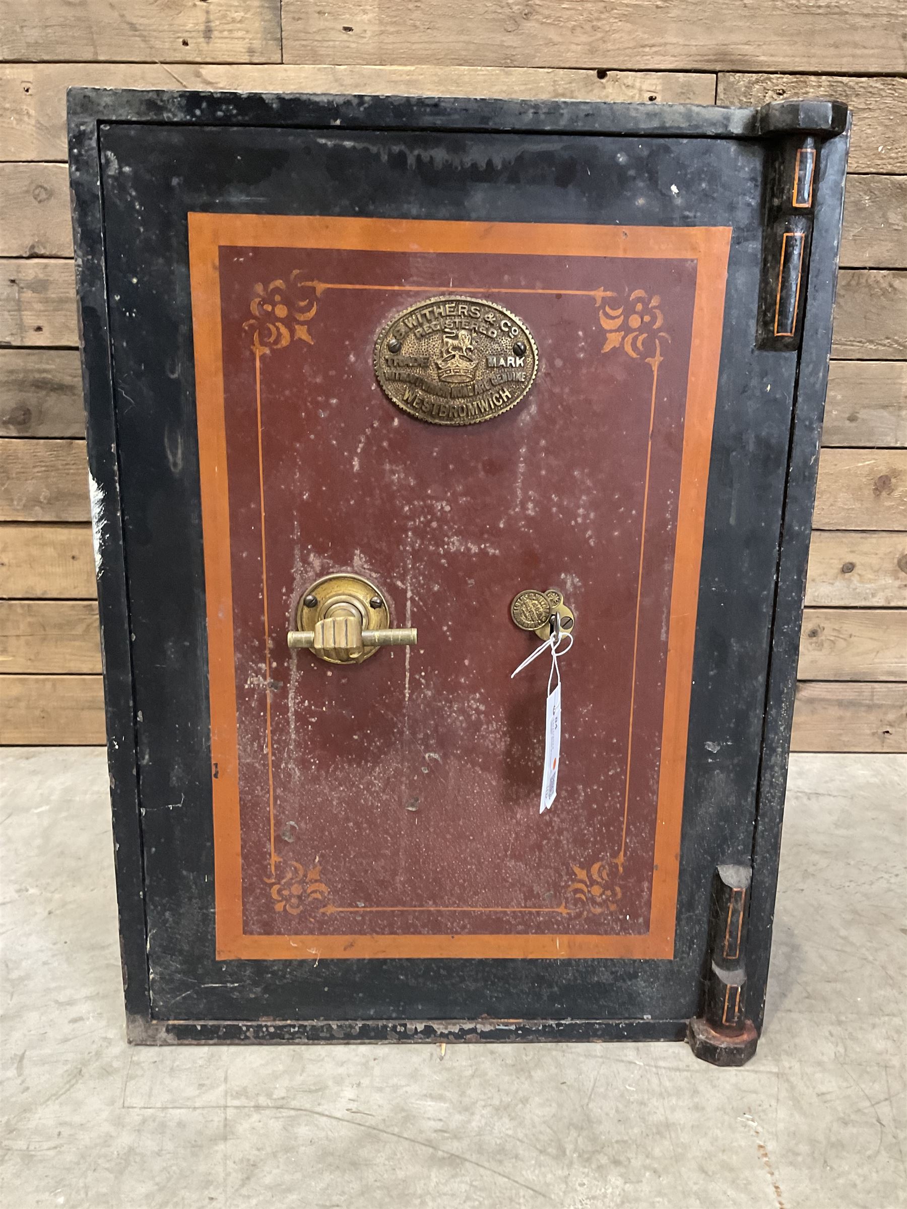 Samuel Withers & Co of West Bromwich - Victorian cast iron safe, the brass handle modelled as a clenched fist, painted in red, orange and black, with key. Ground floor delivery only, no steps.