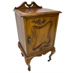 Edwardian Art Nouveau walnut bedside cabinet, raised broken swan neck back with carved flower heads, single fielded panelled door enclosing single shelf, raised on cabriole supports with ceramic castors
