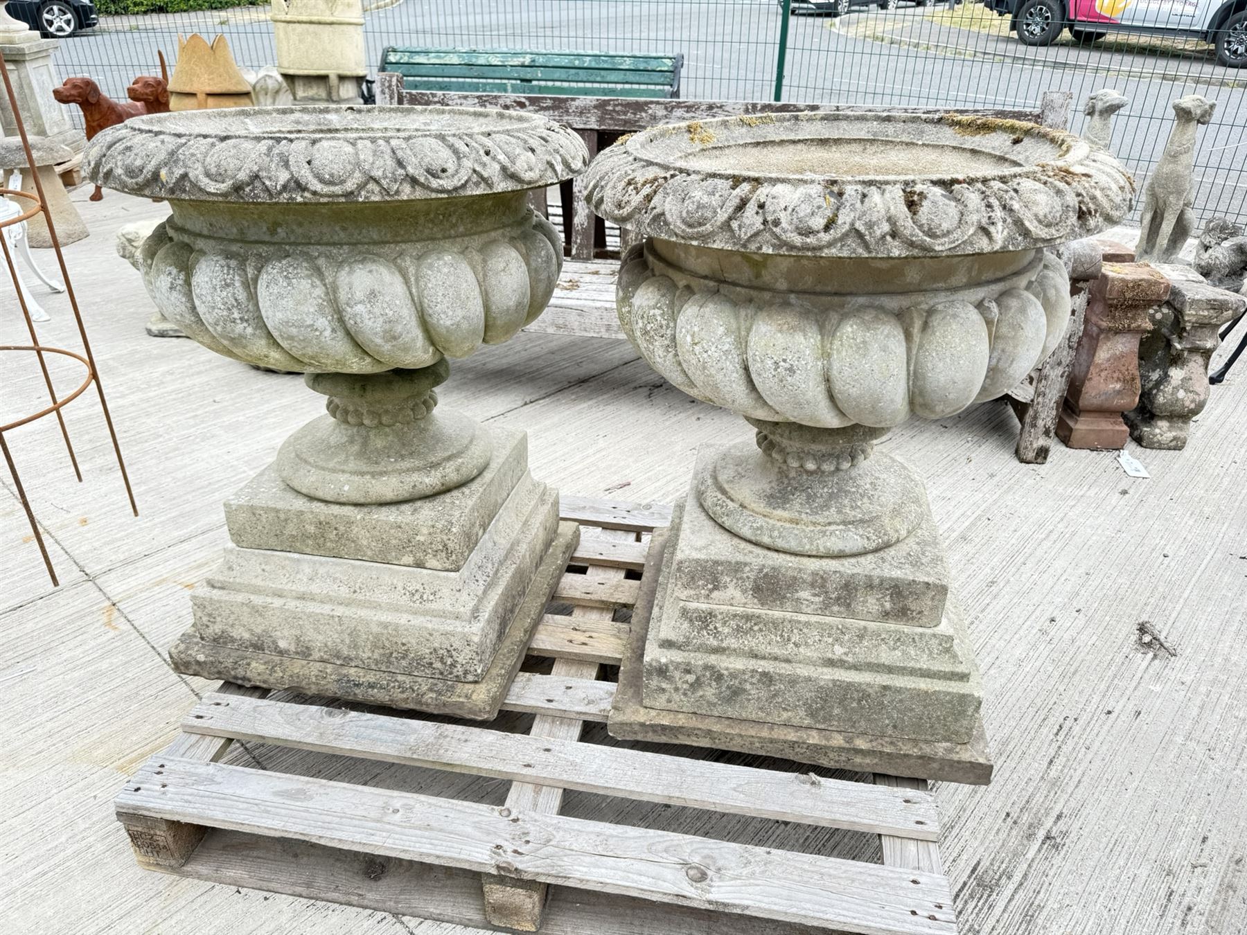 Pair of large weathered Country House Haddonstone garden urns, acanthus carved rim above gadrooned bowl, beaded detailing to the neck, raised on stepped double plinth base
