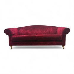Contemporary three-seater sofa, plush upholstered in a deep red velvet fabric, curved back...
