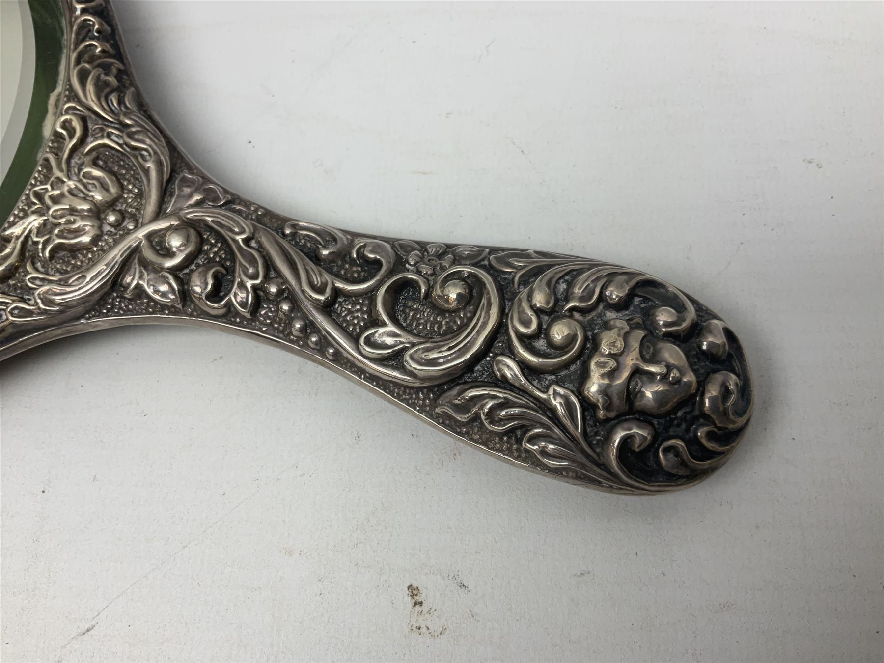 Silver mounted dressing table mirror, embossed with birds, masks, and foliate and C scrolls, hallmarked Birmingham, and fruit knife with mother of pearl handle and silver blade, (2)