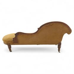 Victorian walnut framed Chaise longue, with carved scroll decoration and an out-swept buttoned upholstered, padded back and scroll end, seat upholstered mustard coloured velvet fabric, raised on turned legs with ceramic castors 
