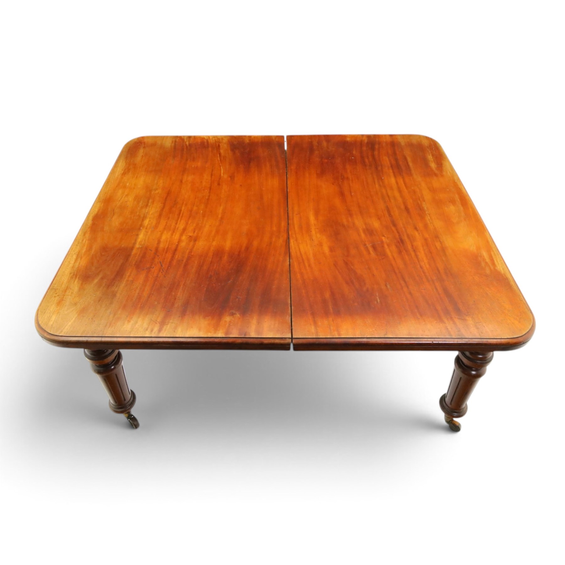 19th century mahogany extending dining table, rectangular top with rounded corners raised on turned and fluted supports with brass cups and castors, with two additional leaves; with set of eight (6+2) Regency design mahogany dining chairs, spiral-reeded back-bar over drop-in seats and sabre supports (W54cm H85cm)