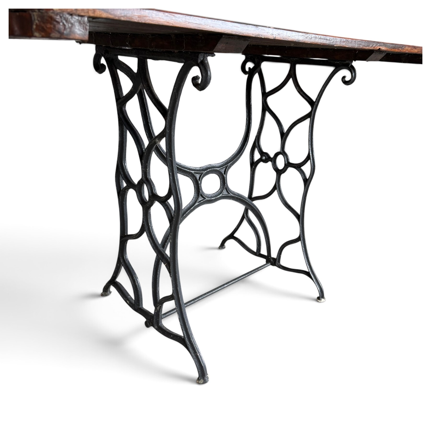 Antique rectangular slatted hardwood garden table, raised on pierced black painted cast iron supports cast with scrolling branchwork and united by pierced curved X-stretcher