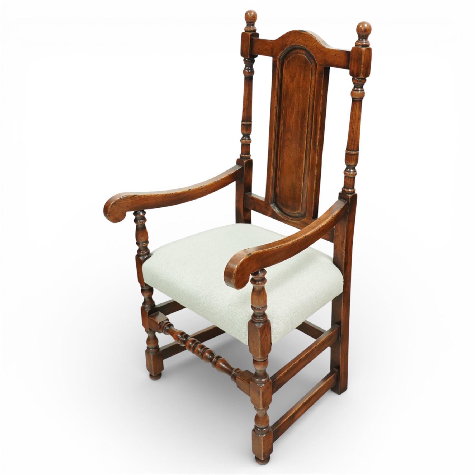 Country House oak high back dining chairs, set of ten comprising eight side chairs and two carvers, each with arched top rail flanked by turned finials over a central fielded panel back, with overstuffed seats upholstered in pale fabric, raised on turned front supports united by stretchers
