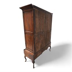 Georgian oak livery cupboard, projecting cornice over panelled front with mahogany bandings, enclosed by two doors, the base fitted with three drawers over shaped apron and cabriole supports 