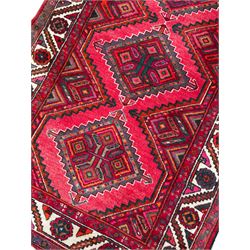 Persian Hamadan red ground rug, decorated with six stepped lozenge medallions, the guarded border with repeating stylised flower head decoration, with inscription to corner