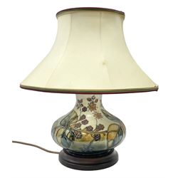 Moorcroft table lamp of squat baluster form, decorated in the Autumn Blackberry, with Moorcroft cream fabric shade with gold, green and red piping, overall H38cm
