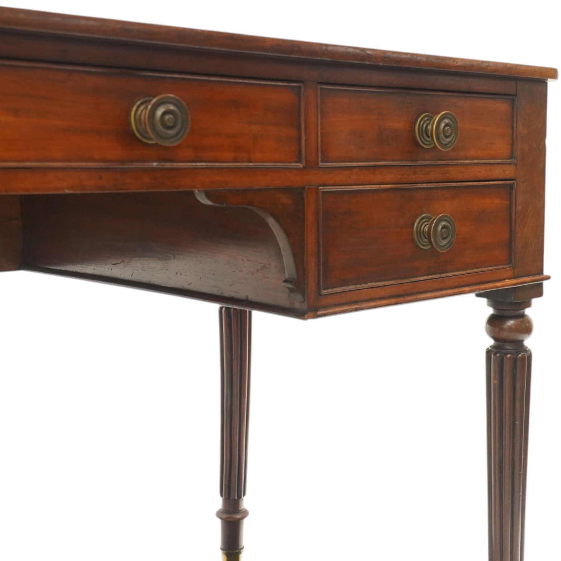 In the manner of Gillows - Regency period mahogany kneehole writing table, rectangular top over central cock-beaded frieze drawer with shaped spandrels, flanked by two graduating drawers to either side, raised on turned and fluted supports terminating to brass cups and castors