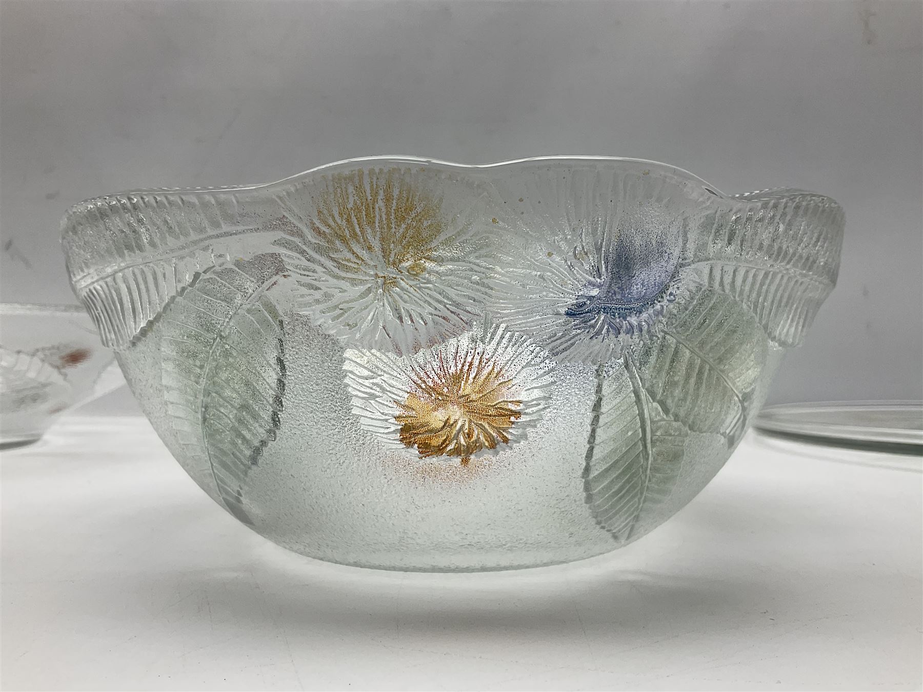 Two French pressed glass bowls of shallow circular form, relief moulded with flowers and foliage, together with a matching charger, largest bowl D34cm  