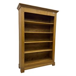 Contemporary French provincial design oak open bookcase, with projecting moulded cornice above a boarded back, fitted with four adjustable shelves, on bracketed plinth base
