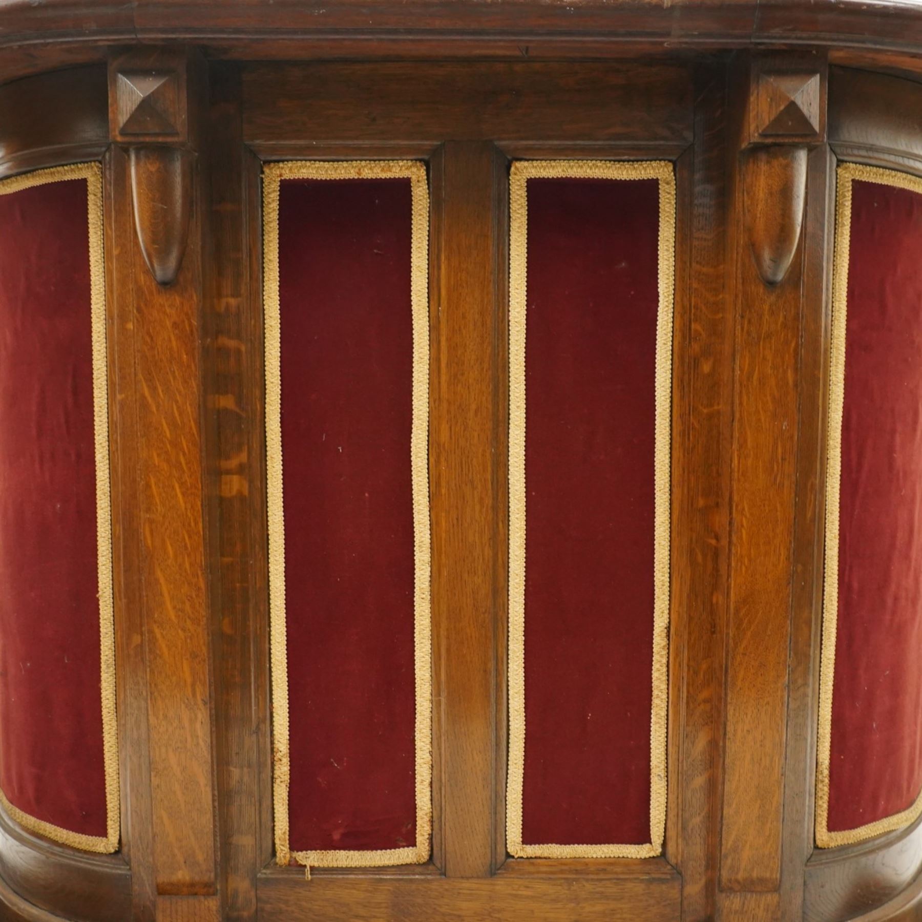 Arts & Crafts oak D-shaped bar, moulded edged counter above a front with velvet applied panels, the back with shelving, raised on a plinth base