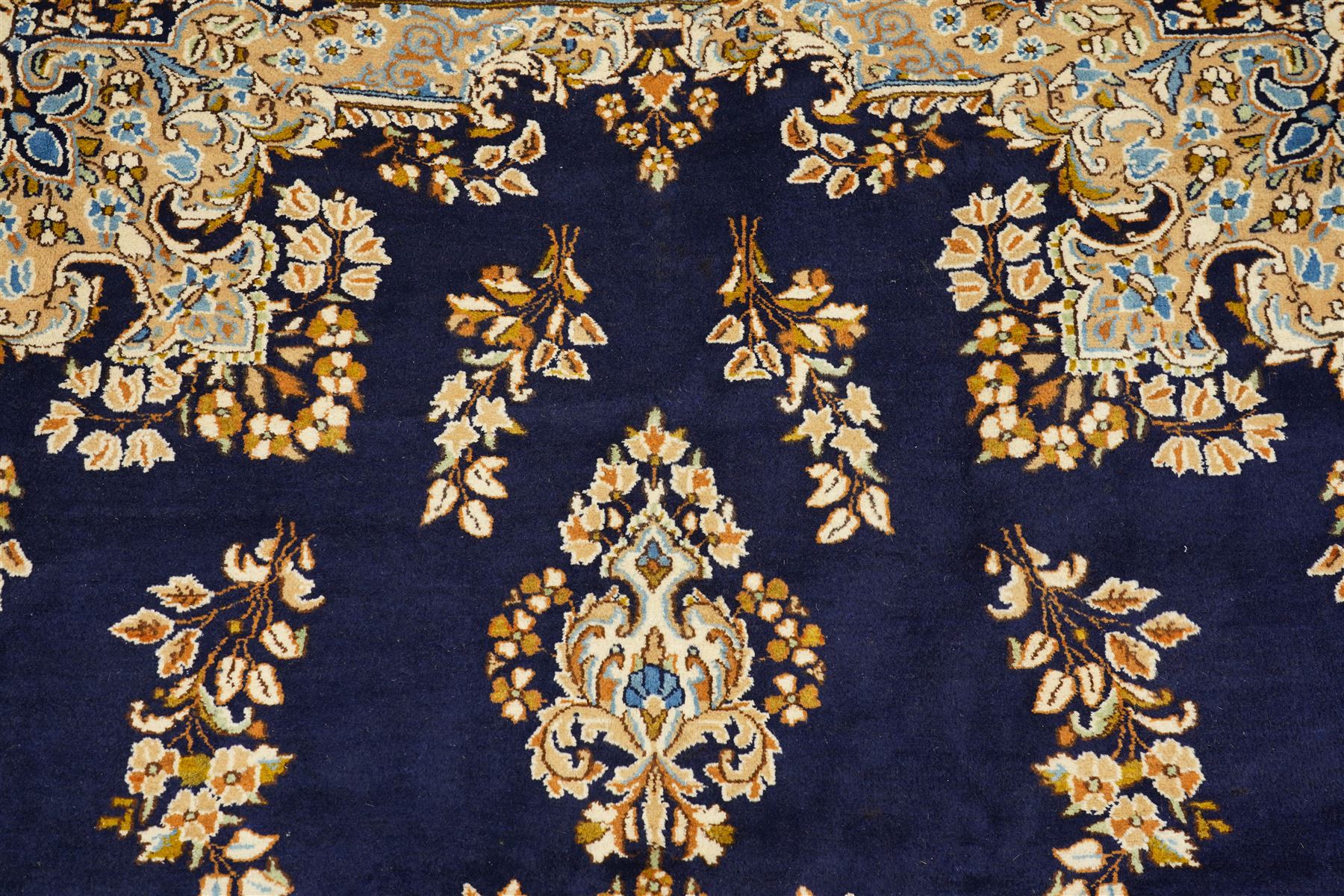 South East Persian Kirman hand-knotted carpet, indigo blue field with central floral medallion in tones of ivory, indigo,  and soft blue, issuing network of scrolling vinery, palmettes and floral sprays, conforming spandrels, broad main border of scrolling foliage and stylized palmettes, framed by multiple guard borders, with cotton fringe ends 